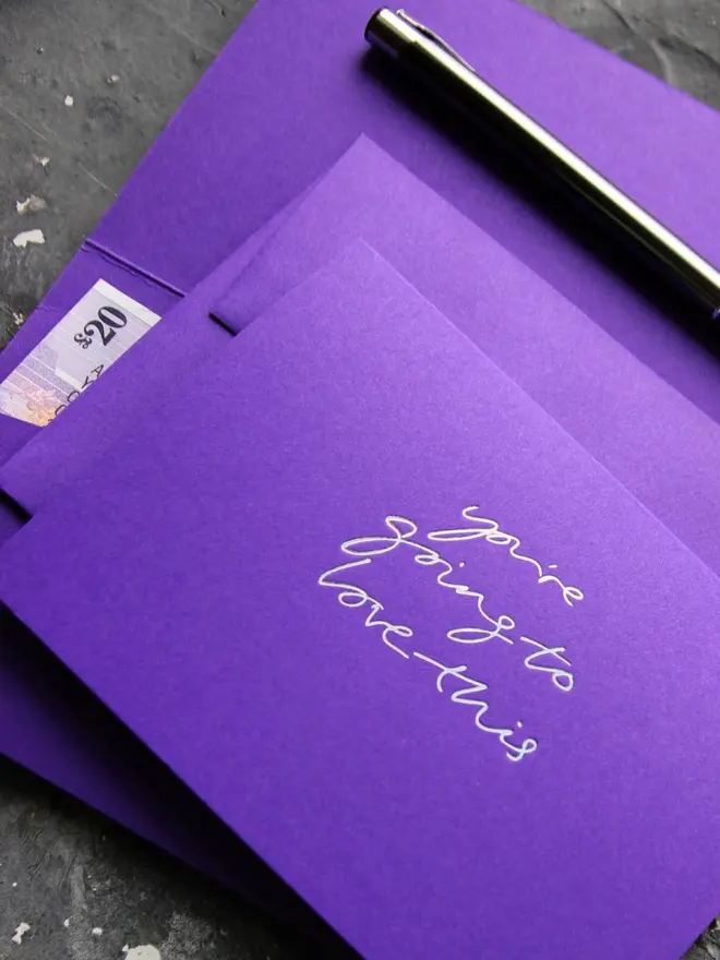 Hand foiled cash card or money wallet in a royal purple colour handfoiled in shiny holographic foil text which says ‘you’re going to love this’.