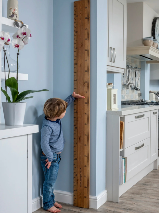 Original Ruler Height Chart. A very large wooden ruler leaning against a wall in a child’s room.