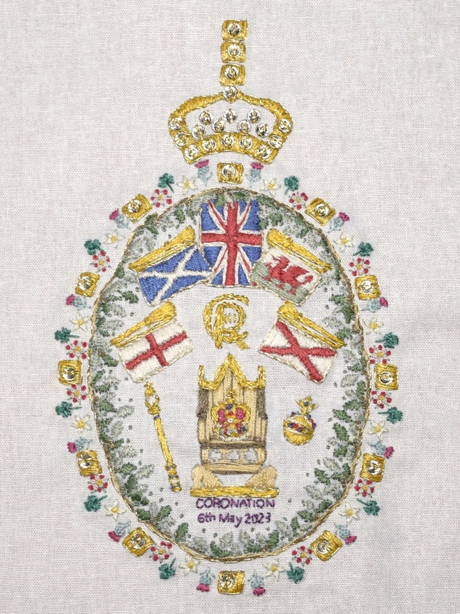King Charles III Embroidery, St Edwards Crown sits on the wooden coronation chair, surrounded by the Orb, Septa, CRIII Cypher, Golden trumpets above with 4 nations flags and the Union Jack.  Framed by British oak leaf wreath and floral emblems.