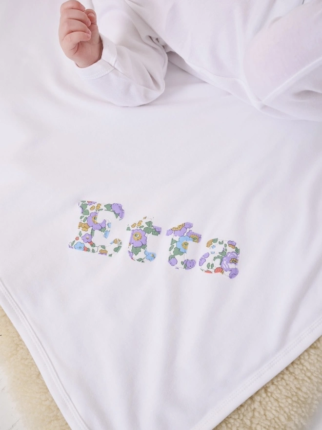 A soft cotton new baby blanket with a name appliquéd on in Betsy Liberty print.