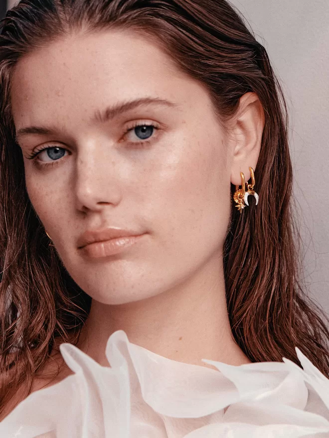 woman wearing earrings with gold charms