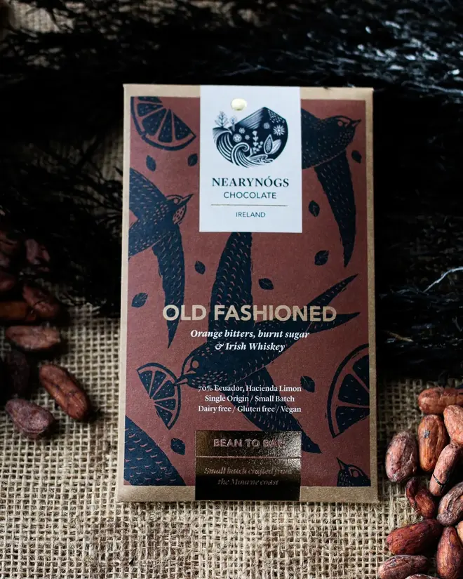 Old Fashioned Irish Chocolate Bar, a chocolate bar sitting on a fabric surface. It is accompanied by some nuts. 