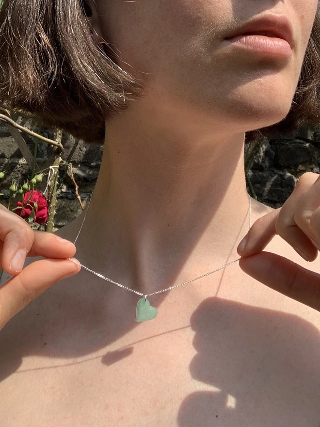 Recycled fishing net heart of a silver chain, necklace being worn by a white women