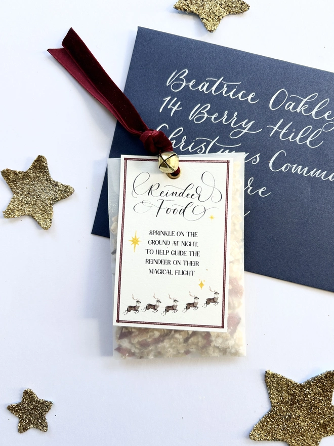 Reindeer food made from oats and dried petals in glassine bag with red velvet ribbon and gold bell and poem label