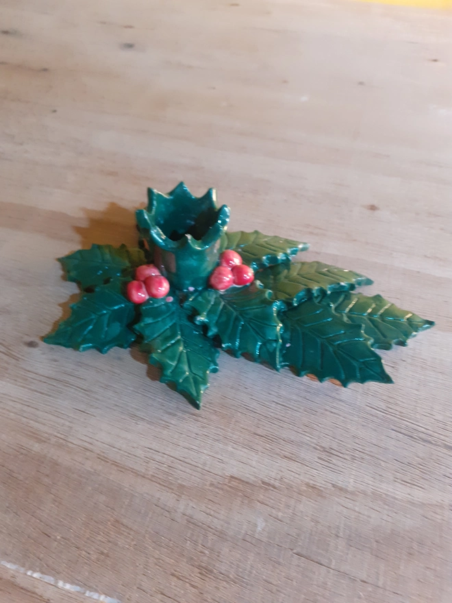 Artisan ceramic holly leaf candle holder without candle, showing the layered leaf detail and shiny glaze finish in festive green and red tones.