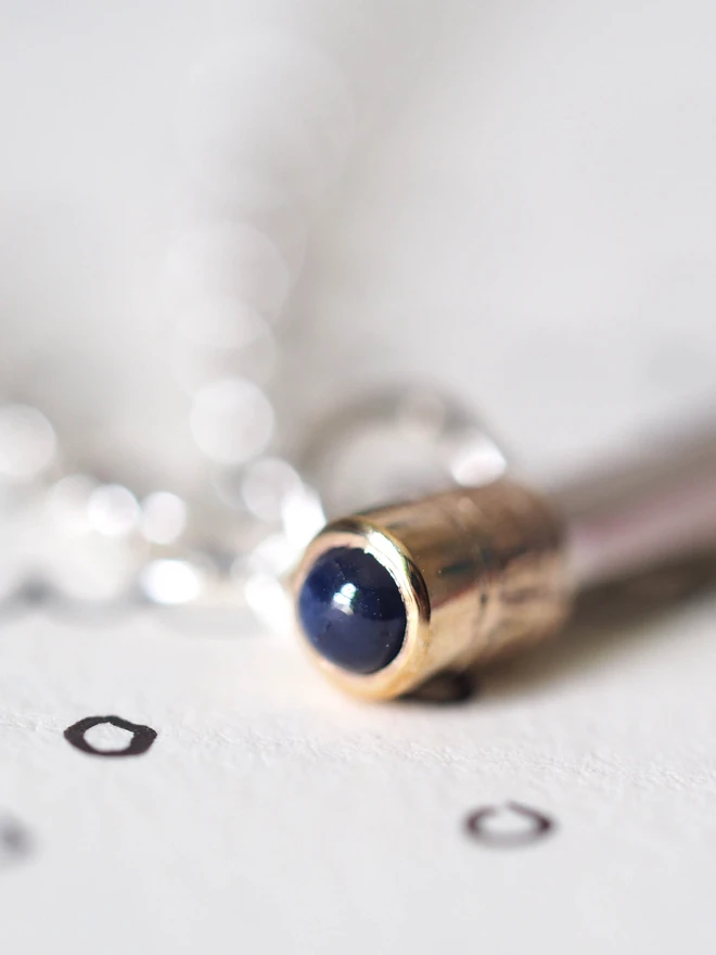Close up image of a sapphire dinky pencil charm on a table