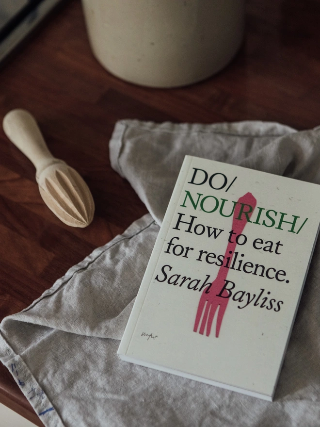 Book on kitchen surface with linen cloth and wooden lemon juicer