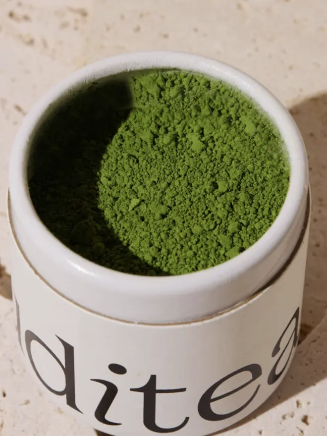 white tub of matcha, open to reveal vibrant green powder inside