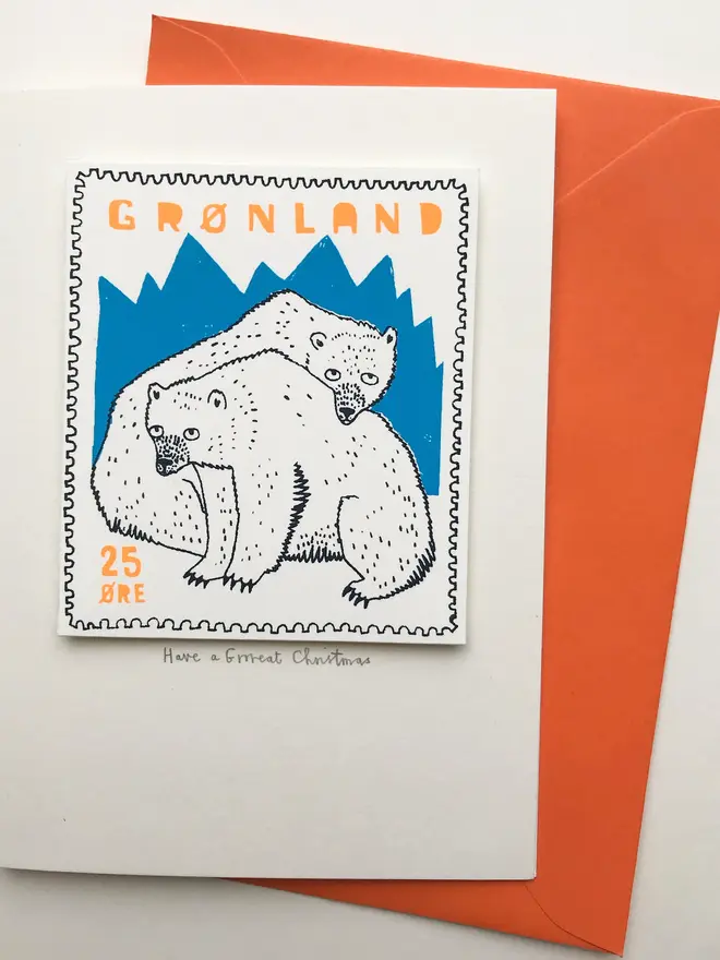 Polar Bear Have A Grrreat Christmas Card, a white card with a colourful polar bear design in the centre on top of an orange envelope on a plain white surface. 