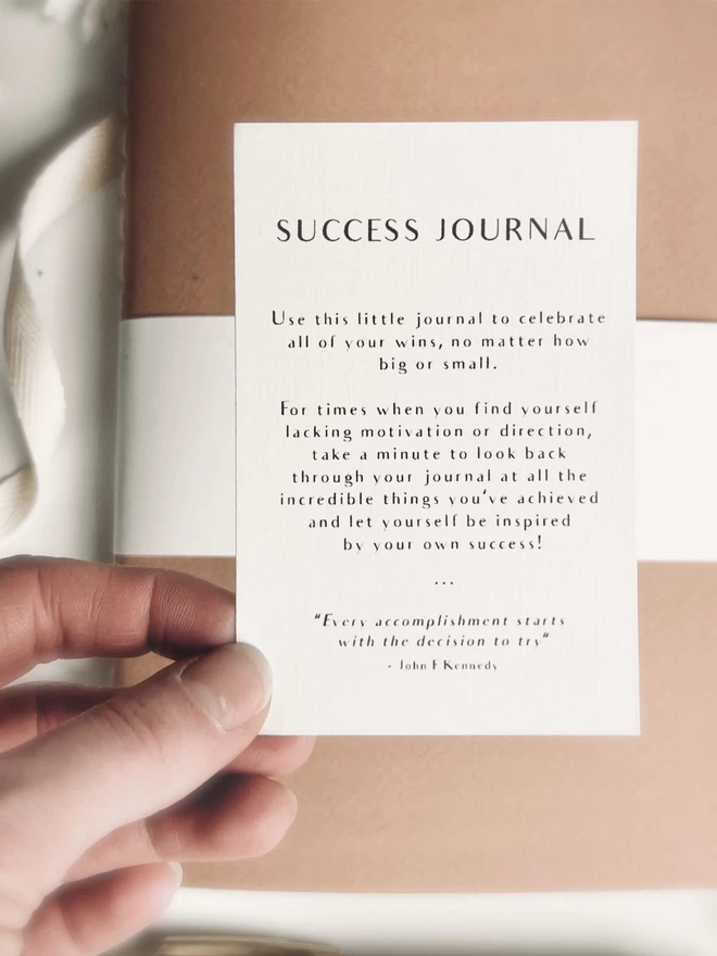 hand holding a slip of paper explaining how to use a success journal 