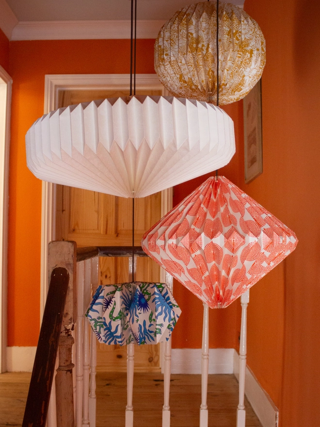 Colourful paper lanterns hang above a wooden staircase with orange walls.