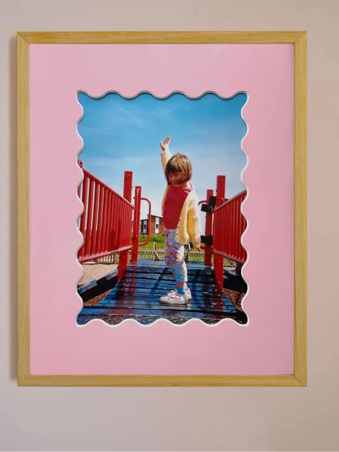 Ric rac photo mount frame with a pink mount featuring a decorative ric rac boarder around a centered Instax photo, displayed on a neutral beige wall.