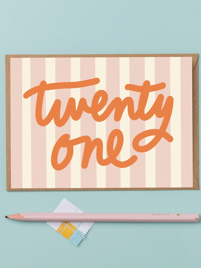 a 21st birthday card featuring the words twenty one in orange lettering on a pink and cream striped background