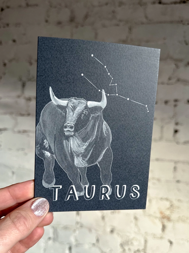 a greetings card featuring a greyscale illustration of a zodiac style bull with the text “TAURUS”