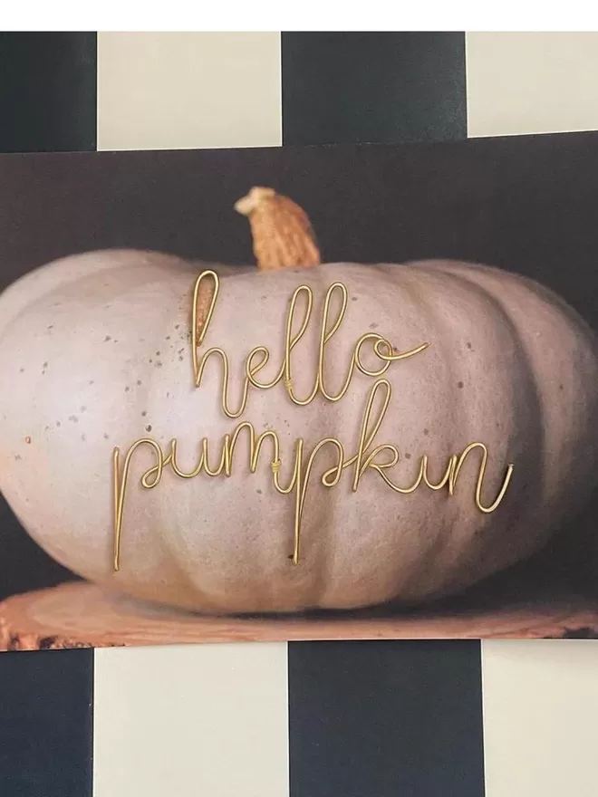 Gold wire sign for halloween seen in a white pumpkin.