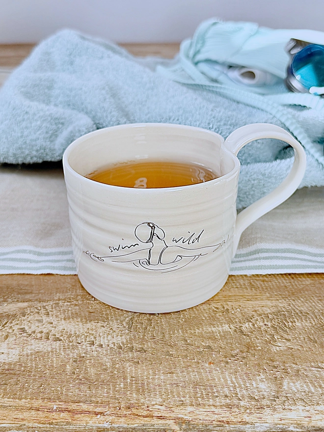 Handcrafted porcelain ‘Swim Wild’ mug – unique ceramic coffee cup for swimmers, nature lovers, and outdoor adventurers.