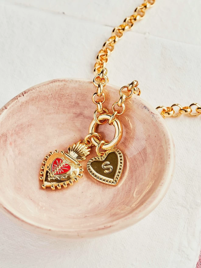 Gold belcher chain with frida kahlo heart and initial charm heart in pink bowl