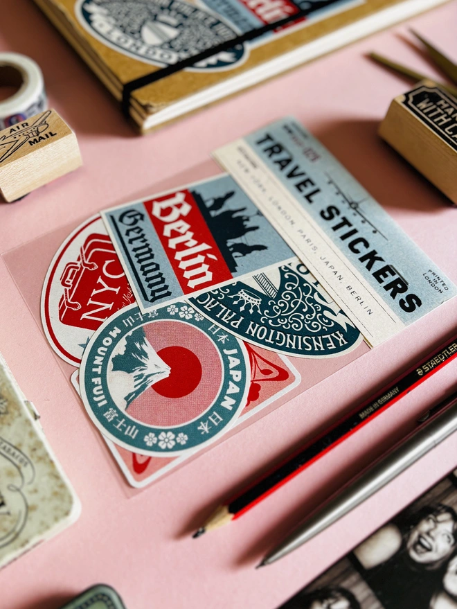 Vintage Travel Stickers for New York, Japan, Paris, London and Berlin in a cellophane bag, surrounded by stationary 
