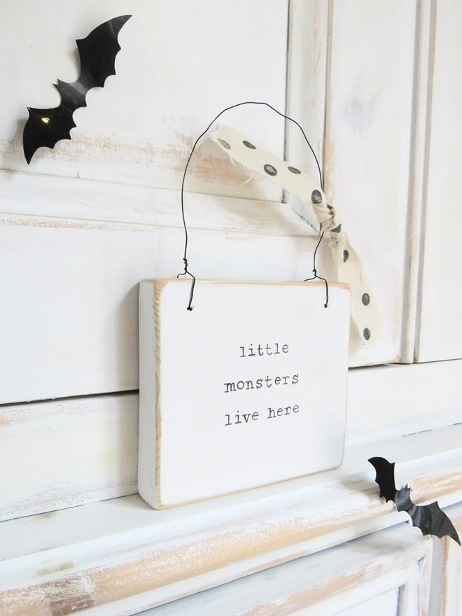 hand painted white wooden sign with hand painted little monsters message