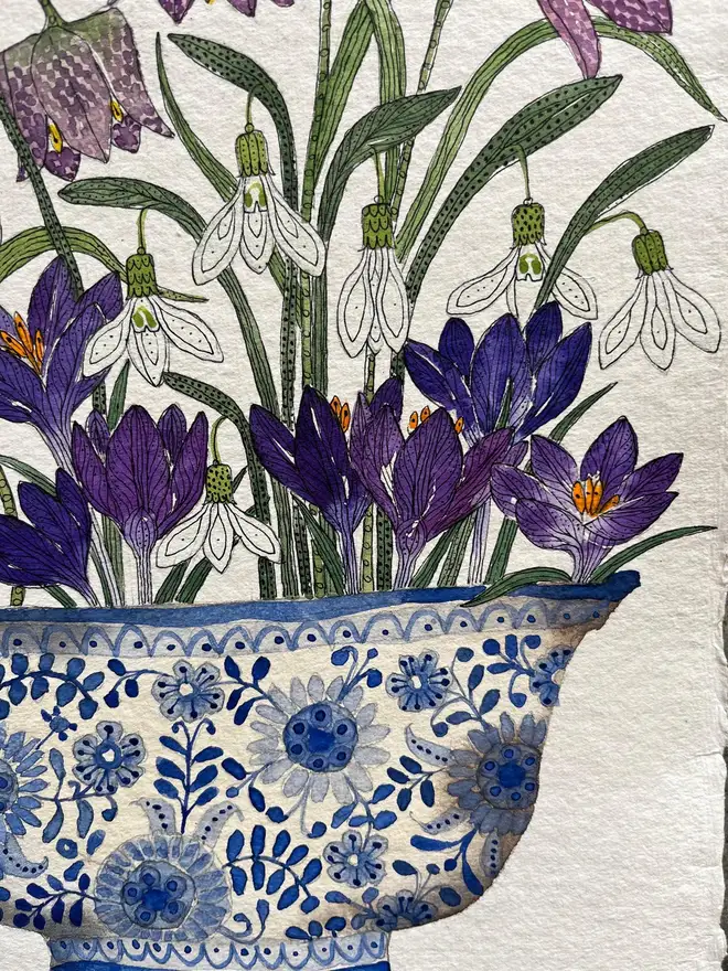 crocus, snowdrops and fritillary flowers in a blue and white, patterned ceramic vessel