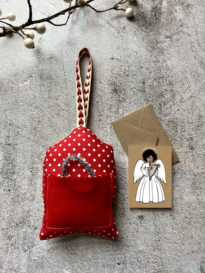 a mini greeting card featuring an illustration of an Afro Caribbean dark skinned angel playing a harp