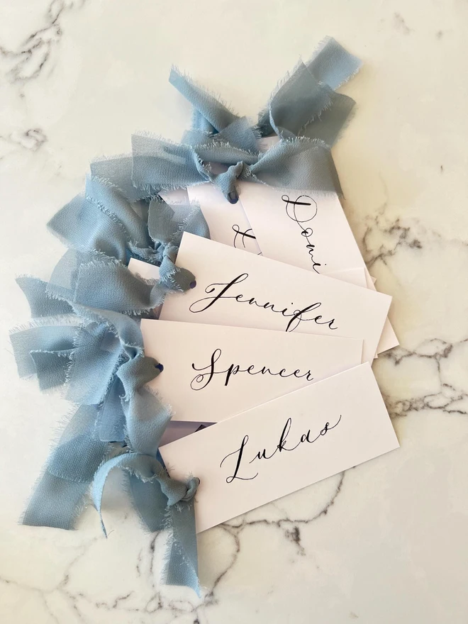 Personalised Calligraphy Wedding White Place Cards, white place cards with dusky blue chiffon ribbon. 