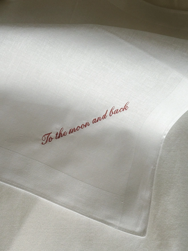 white handkerchief with embroidered red text