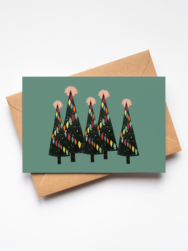 A deep green greeting card featuring a forest of decorated Christmas trees.