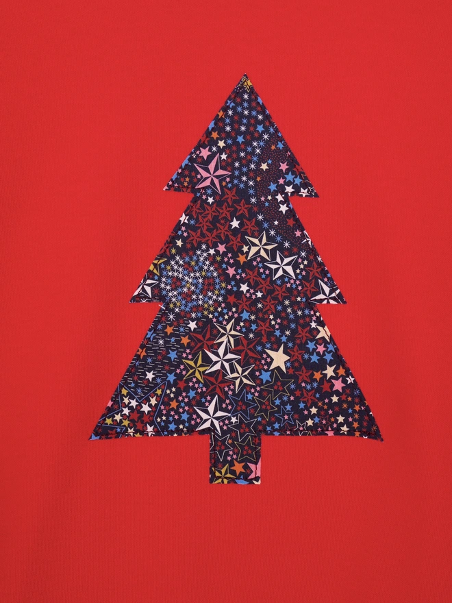 a close up of a red tee with a christmas tree cut from starry liberty print sewn onto the front