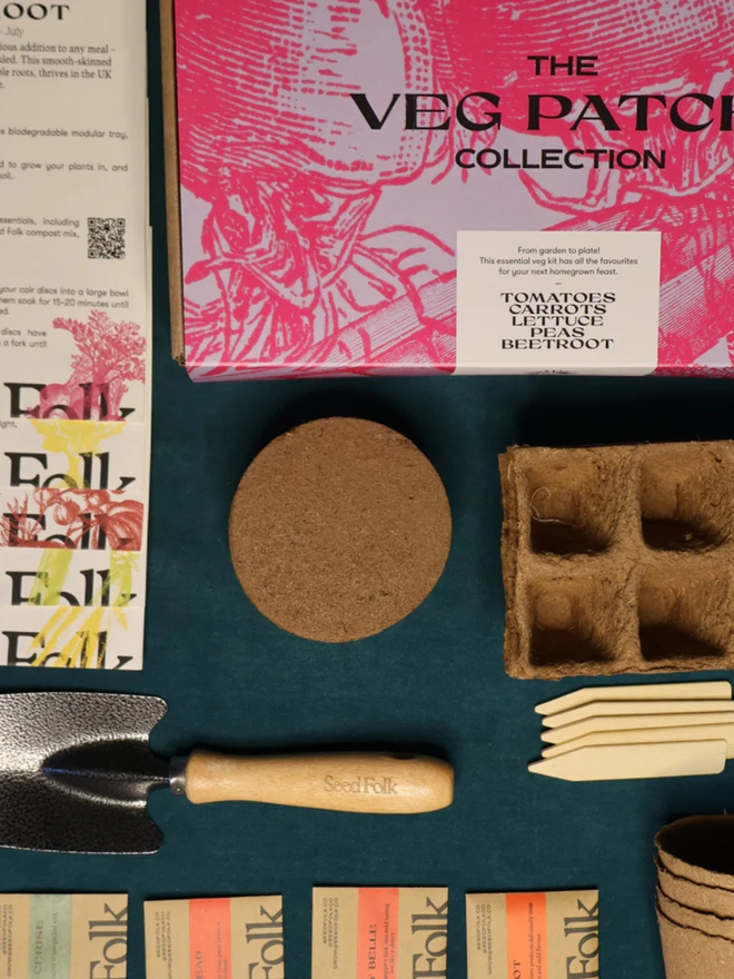 the seed growing starter kit. box in a decorative pink sleeve photographed alongside gardening supplies inside.