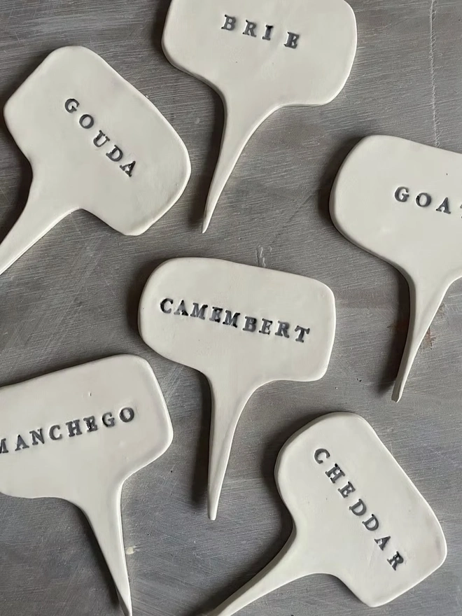 Ceramic Cheese Markers, a group of ceramic cheese markers grouped on a plain surface. 