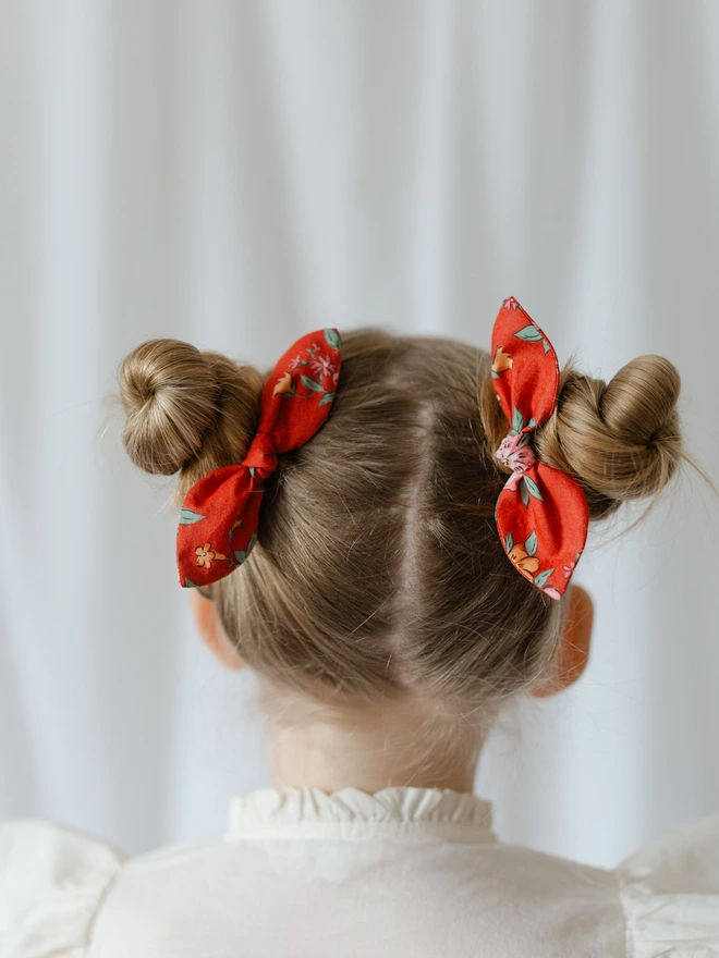 Girl with two little buns and red liberty hair bobbles 