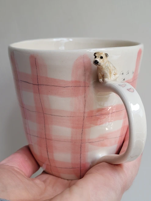 pink gingham cup with tiny border terrier dog pawprints and hearts held in a hand looking rather lovely