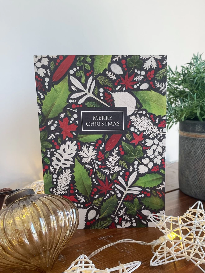 Christmas Card with Pressed Winter Leaf Design - Holly, Ivy - Wooden Bookcase with Vintage Bauble, Star Lights, Potted Plant