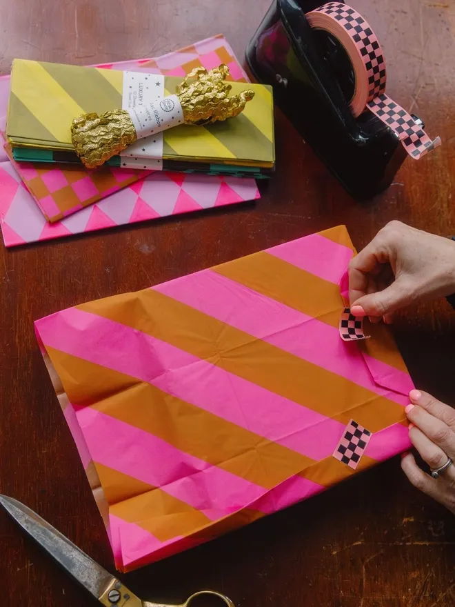 Stripey tissue paper wraped gift in flouro pink and ginger