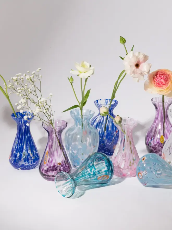 group shot of purple, pink, and blue glass vases with flowers