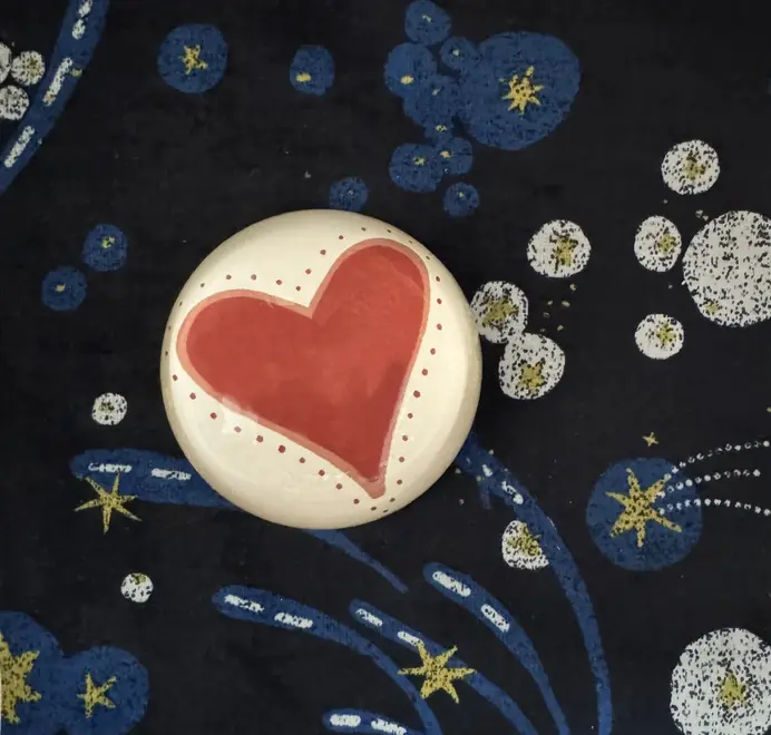Round paperweight with a red heart on a starry blue background.