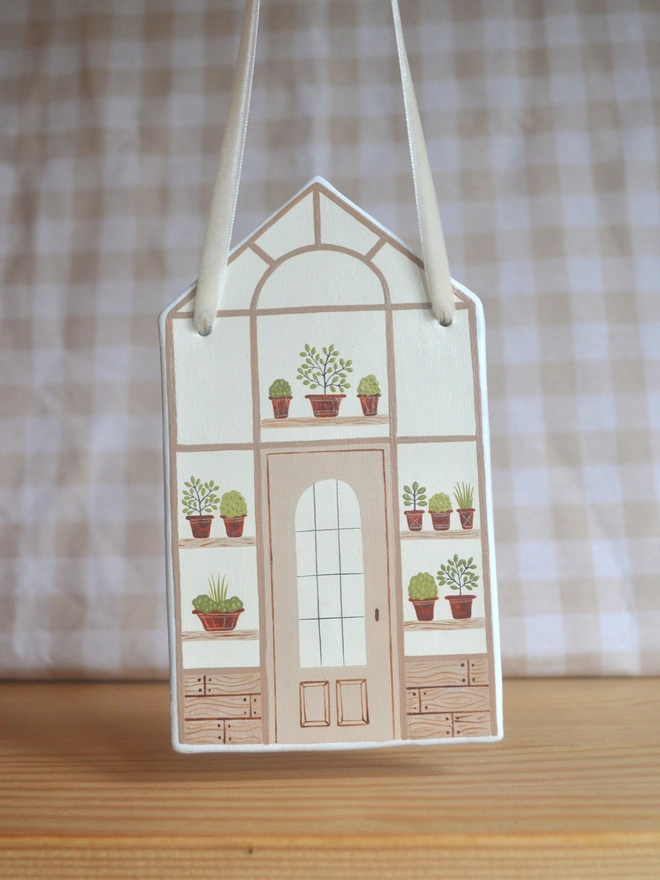 white ceramic hanging decoration with brown greenhouse illustration design