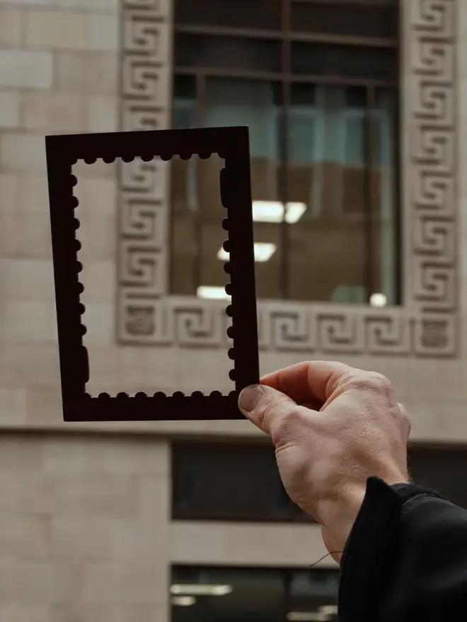 person holding an empty black stamp shaped frame mount