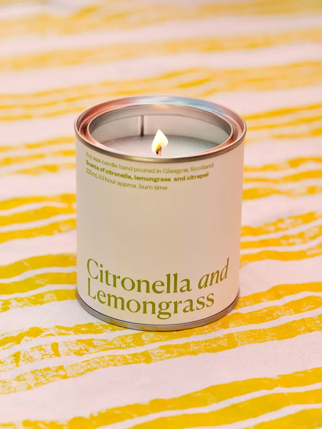 Citronella and Lemongrass Soy Wax Candle Candle, displayed on a yellow and white stripped tablecloth 