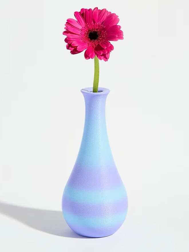 3d printed vase in blue and purple stripes with bright pink flower