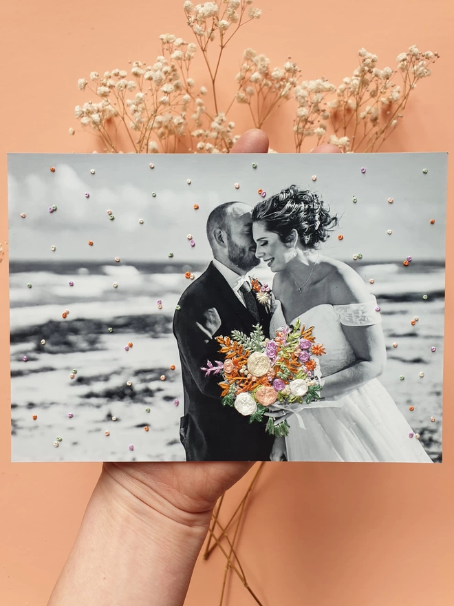Wedding photo in B&W with hand embroidered bouquet & confetti held against peach background
