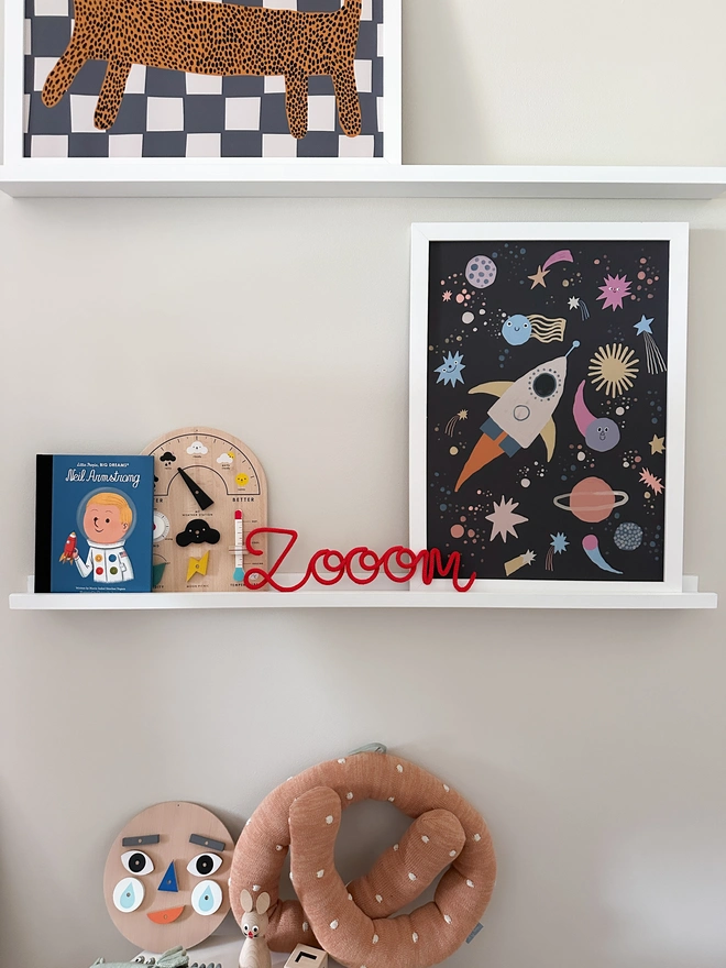Zoom kids sign propped on a shelf in a child's bedroom with a space themed print and some other childrens toys.