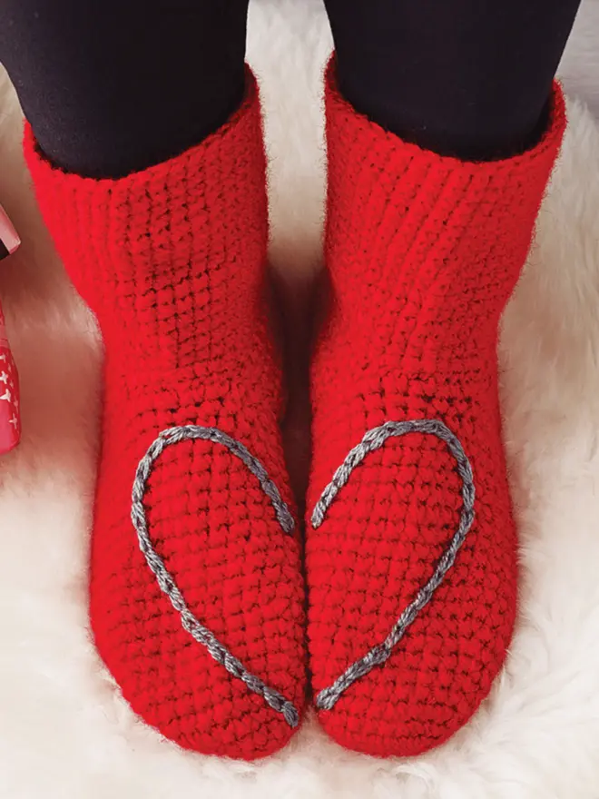 Red slipper socks with grey heart embroidered on which shows when feet stand together