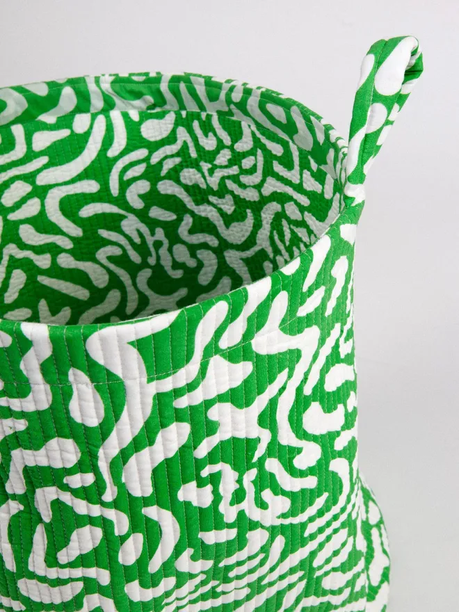 Close up of Green Golf Course Quilted Storage Basket, a green pattern basket sitting against a grey backdrop.