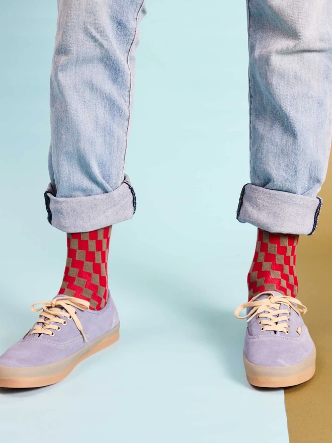 man wearing red and grey checked socks, jeans and blue shoes