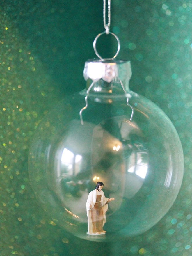 Miniature figure of Jesus in a glass Christmas bauble (part of nativity scene)