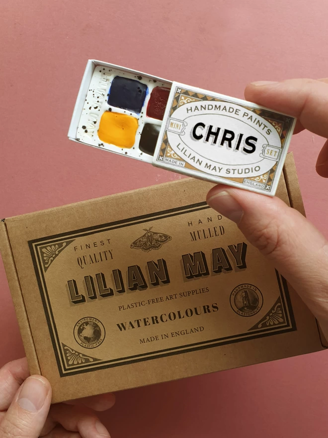 A watercolour paint set being held with it's printed box packaging.