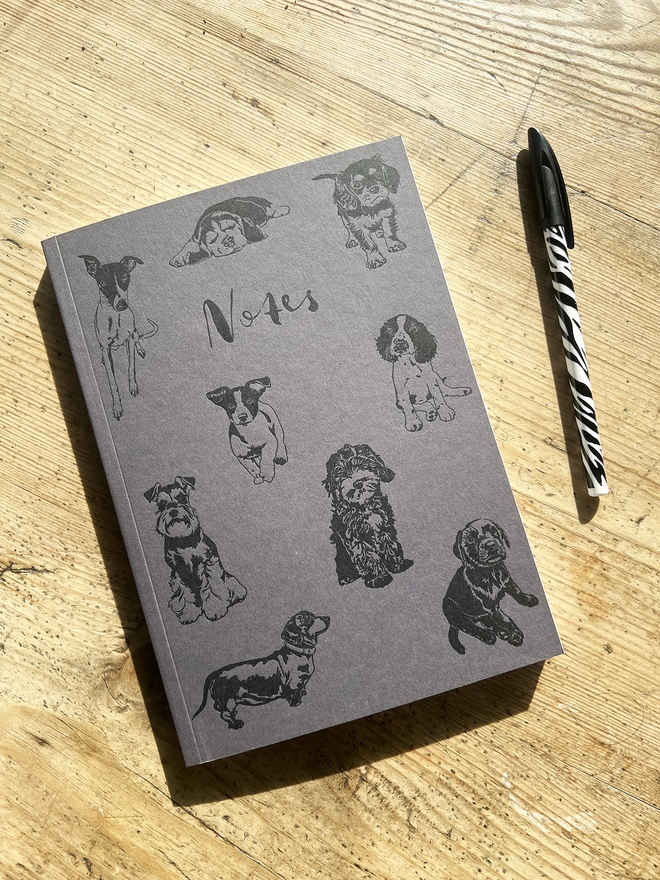 Letterpress puppy notebook with pen next to it.