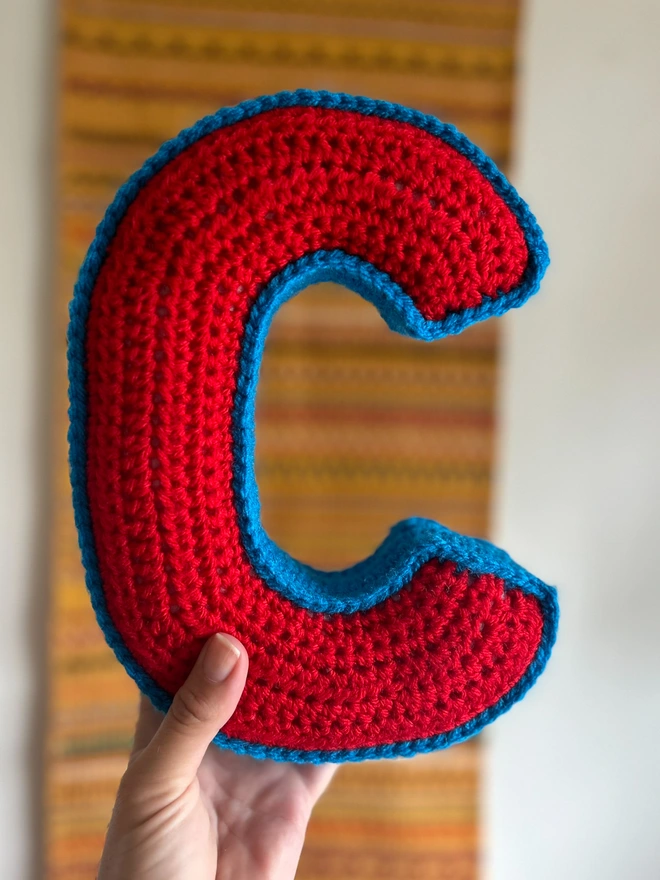 Crochet cushion in shape of letter C in red and blue